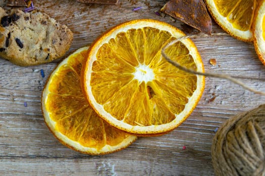 Dried oranges, chocolate slices, chocolate biscuits and cinnamon on a wooden table.