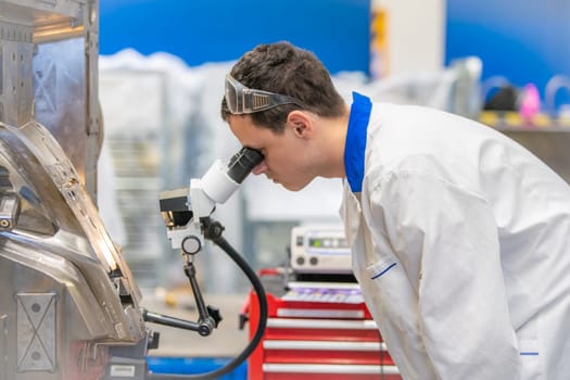 using a microscope while working in a research center.