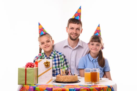 Happy dad and two daughters at the festive table in honor of the birthday