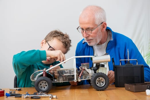 grandpa and son little boy repairing a  model radio-controlled car at home