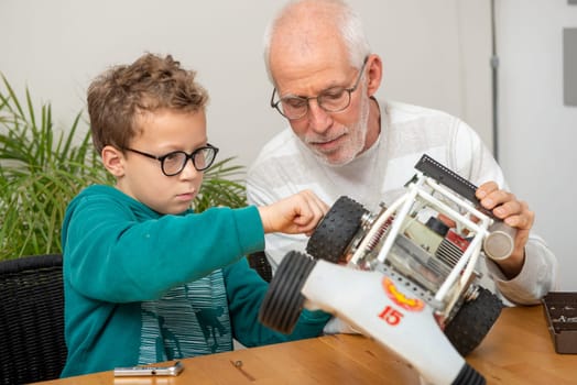 grandpa and son little boy repairing a  model radio-controlled car at home