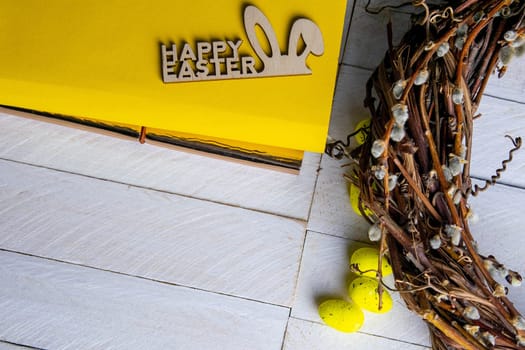Easter concept. Yellow notepad with a sign of the sorly Easter and a wreath stand on a white wooden table.
