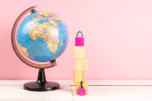 Globe and wooden cubes lined in the shape of a house, along with a pink pad and keys. The concept of renting a home.