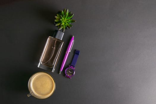 Women's parfums together with coffee with milk and green flower, next to there are purple watches and a pen top views with clear space
