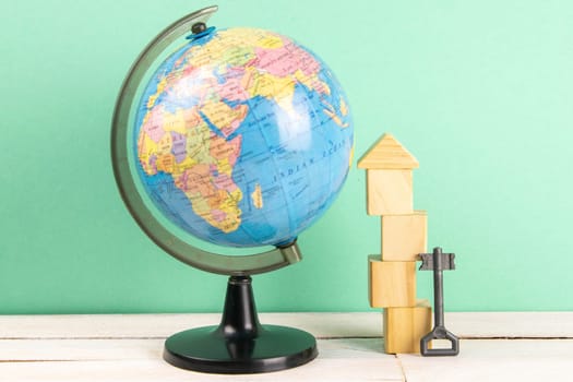 Globe and wooden cubes lined in the shape of a house, along with a pink pad and keys. The concept of renting a home.