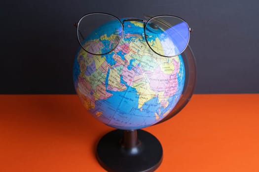 Glasses clad on the globe which stands on an orange background.