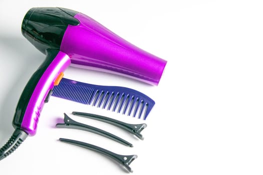 Professional lad's kit on a white background, purple hairdryer, hairpins and sprouts.