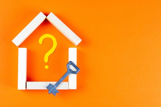 The house is made of wood bars inside a painted question mark, and next to stands the key.