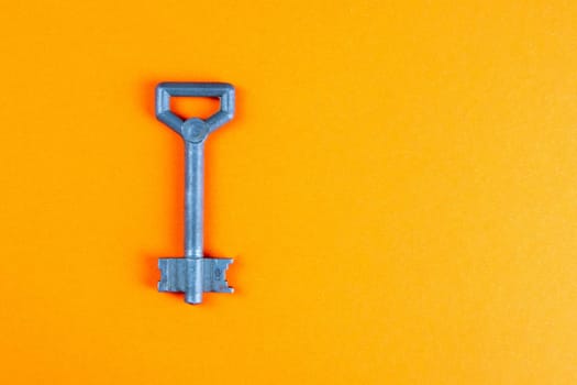 Metal old key on an orange background. Top views with clear space
