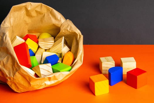 Colorful wooden cubes scattered on an orange table. Most of which is in the craft package.