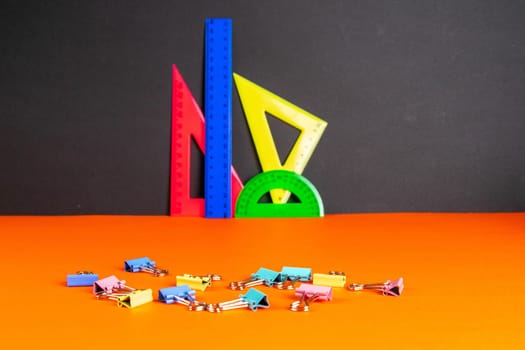 Back to school. Multicolored rulers on a black background. Copy space for text.