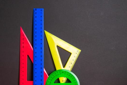 Back to school. Multicolored rulers on a black background. Copy space for text.