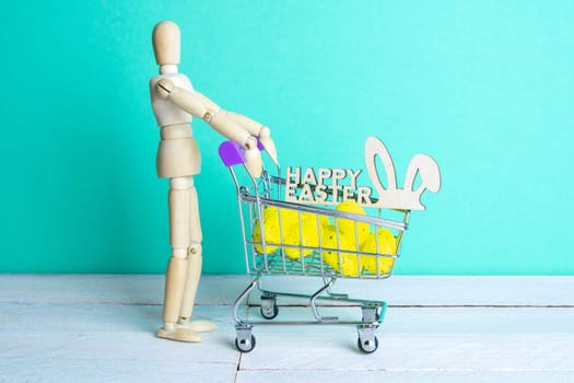 The Easter concept. Figure of a wooden man with a basket filled with eggs. In the background is a wooden rabbit and a sign of a Happy Easter.