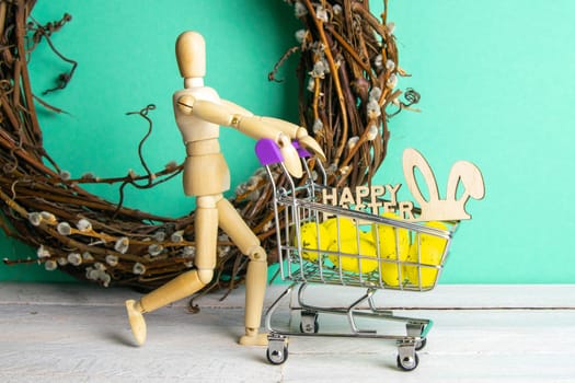 The Easter concept. Figure of a wooden man with a basket filled with eggs. In the background is a wooden rabbit and a sign of a Happy Easter and a wreath.