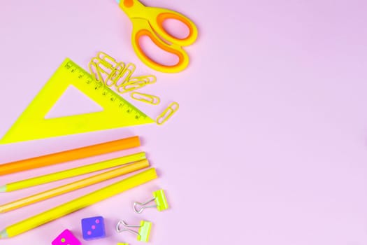 Multi-colored red yellow pinc pencils rulers, pens, pencils and scissors and stationery stand on a pink background.