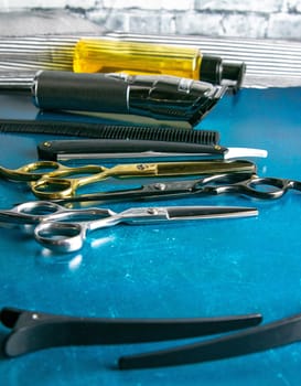 Hairdressing tools, scissors, hair clipper, comb, dangerous razor, hair gel stand on blue background.