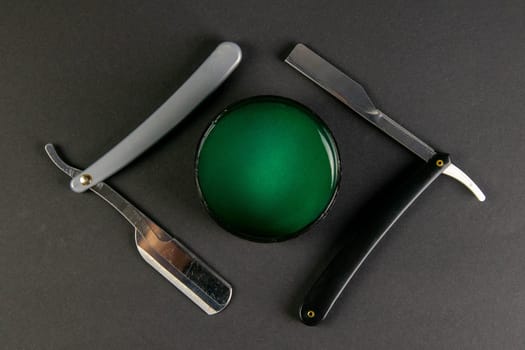 Dangerous razor and a gel for haircuts stand on a black table, the concept of barber shop.