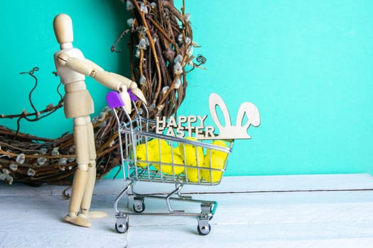 The Easter concept. Figure of a wooden man with a basket filled with eggs. In the background is a wooden rabbit and a sign of a Happy Easter and a wreath.