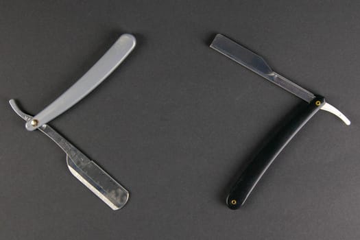 Two dangerous razors on a black table the concept of barber shop.