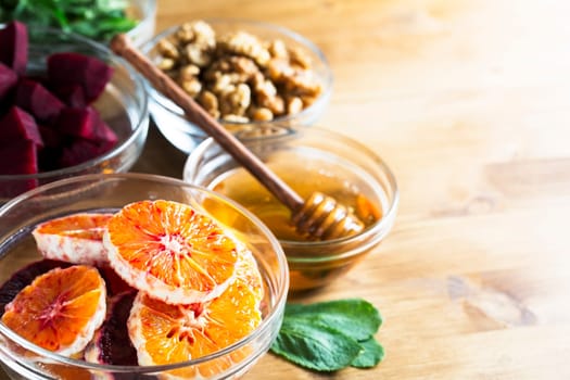 Oranges, honey, beetroot, walnuts and mint leaves on table.