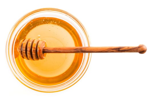 Honey in glass bowl with wooden dipping stick, isolated on white.