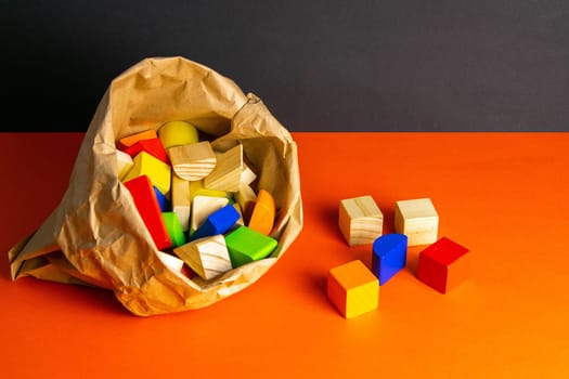 Colorful wooden cubes scattered on an orange table. Most of which is in the craft package.