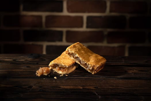 Two apple cake on wooden table and brick wall background