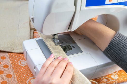 Female hands work on a sewing machine, sewing coffee towel. Close-up.