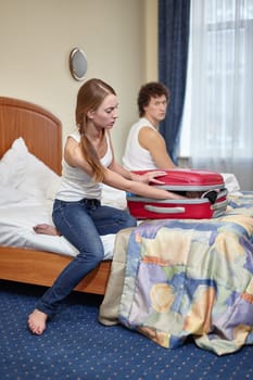 Family problems.  Divorce. Young woman packing  things in suitcase is going to leave the husband. Family conflict. Selective focus on woman