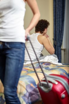 Family problems. Divorce. Young woman with a suitcase leaves from the husband. Family conflict. Selective focus on man