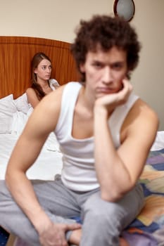 Family problems. Young couple quarrels in bedroom at home. Family conflict. Selective focus on woman