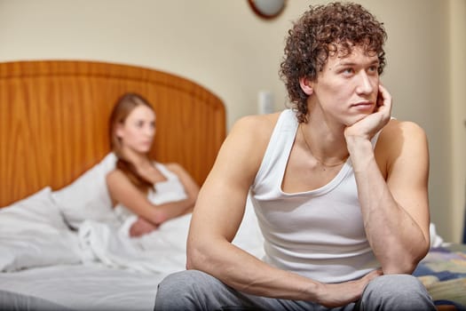 Family problems. Young couple quarrels in bedroom at home. Family conflict. Selective focus on man