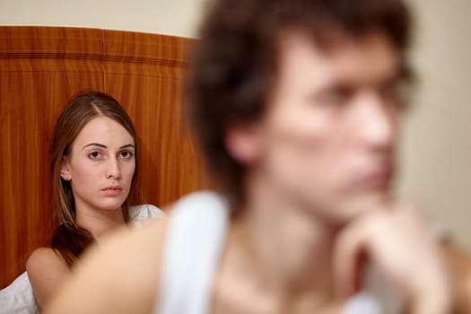 Family problems. Young couple quarrels in bedroom at home. Family conflict. Selective focus on woman