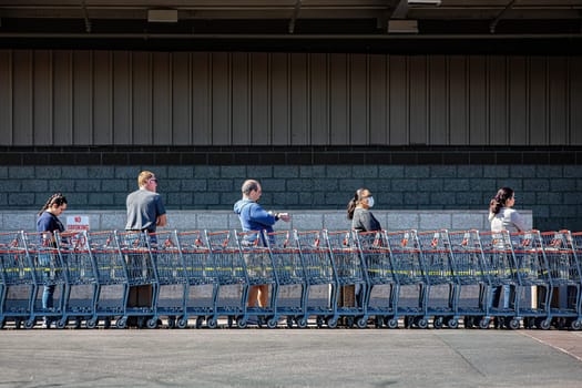 TUCSON, UNITED STATES  - March 29: Five unidentified shoppers practicing social distancing lined up outside retail warehouse store in Tucson during the coronavirus pandemic.. March 29, 2020 in Tucson, Arizona, USA.