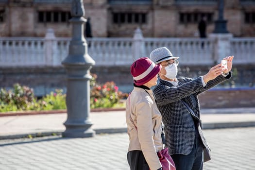 SEVILLE, SPAIN  - March 7: Unidentified couple with man wearing mask to protect himself and others from coronavirus take selfie. March 7, 2020 in Seville, Spain.