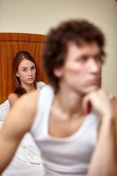 Family problems. Young couple quarrels in bedroom at home. Family conflict. Selective focus on woman
