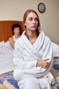 Family problems. Young couple quarrels in bedroom at home. Family conflict. Selective focus on woman