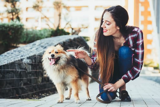 Young woman showing her dog with hand. Copy space for text