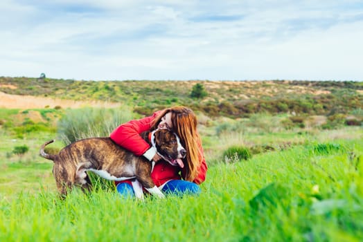 Attractive smiling woman hugging her nice dog. American Stranfrod