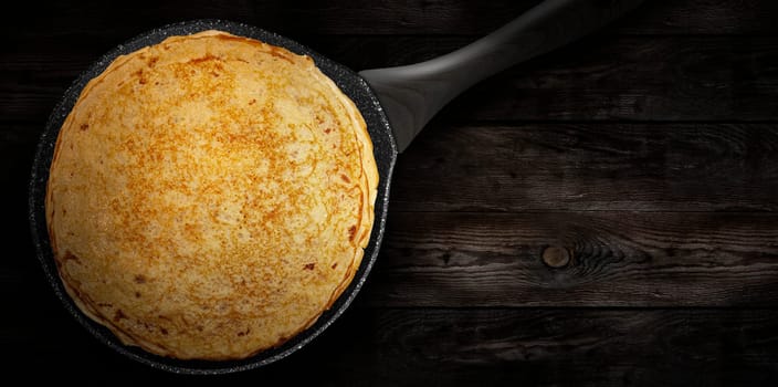 Homemade pancakes on a pan on a wooden plank. Pancake week. Delicious breakfast. View from the top.