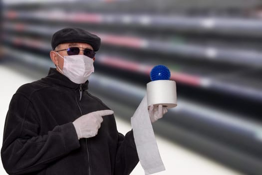 Coronavirus panic concept. Man with surgical mask, hood, glasses and medical gloves shows a roll of toilet paper with an abstract model of a virus covid-19 on it against blurred super market background.