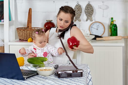 Mother with notebook and little child sit at dining table in home kitchen. Isolation period, quarantine, social distancing. Remote education or remote work