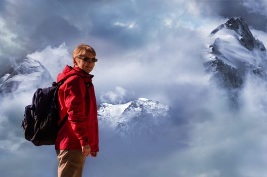Female caucasian mountain climber in front of peaks with snow and clouds