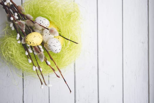 Easter decorations. Willow twigs and decorative Eggs in nests on white wooden background