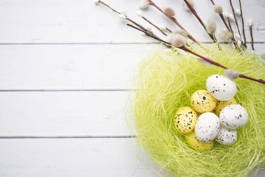 Easter decorations. Willow twigs and decorative Eggs in nests on white wooden background