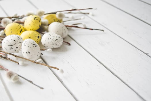 Easter decorations. Willow twigs and decorative Eggs on white wooden background