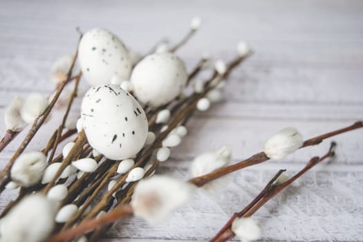 Easter decorations. Willow twigs and decorative Eggs on white wooden background