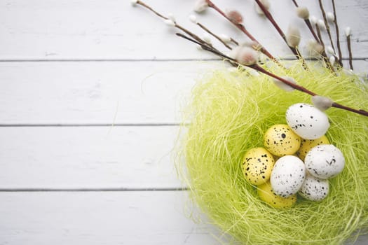 Easter decorations. Willow twigs and decorative Eggs in nests on white wooden background