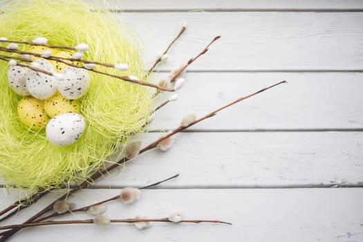 Easter decorations. Willow twigs and decorative Eggs in nests on white wooden background