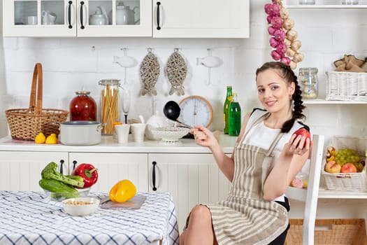 Young woman in an apron is cooking healthy food in the kitchen.